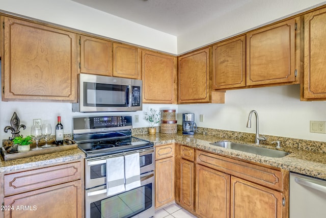 kitchen featuring light stone counters, sink, light tile patterned floors, and stainless steel appliances