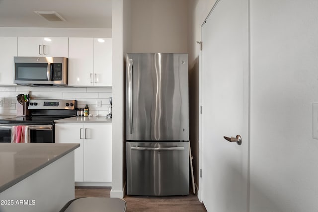 kitchen featuring white cabinetry, appliances with stainless steel finishes, dark wood-type flooring, and backsplash