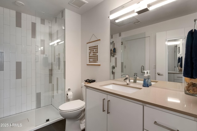 bathroom featuring vanity, toilet, and tiled shower