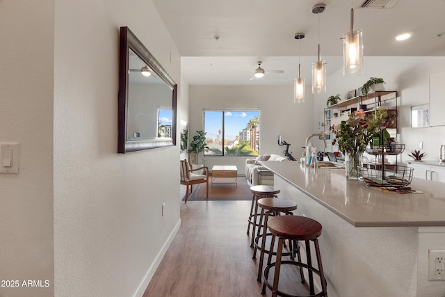 kitchen featuring a kitchen bar, sink, hanging light fixtures, dark hardwood / wood-style flooring, and ceiling fan