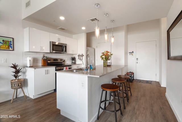 kitchen with tasteful backsplash, hanging light fixtures, stainless steel appliances, and white cabinets