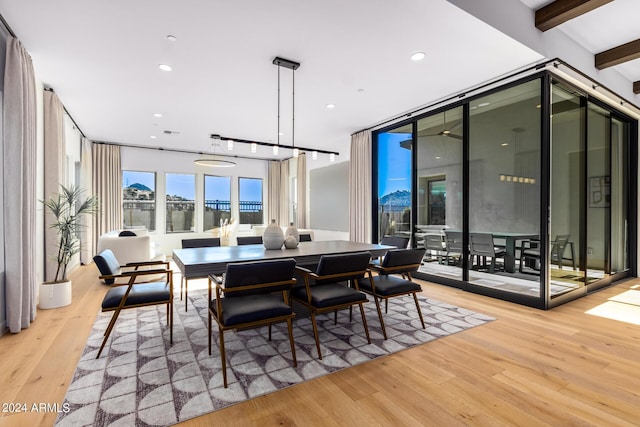 dining space featuring beam ceiling, light hardwood / wood-style flooring, and a wall of windows