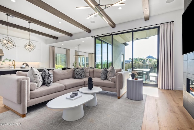 living room featuring beam ceiling, sink, light hardwood / wood-style flooring, and a wealth of natural light