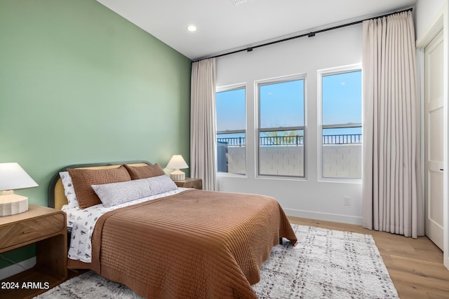 bedroom with a water view and light wood-type flooring