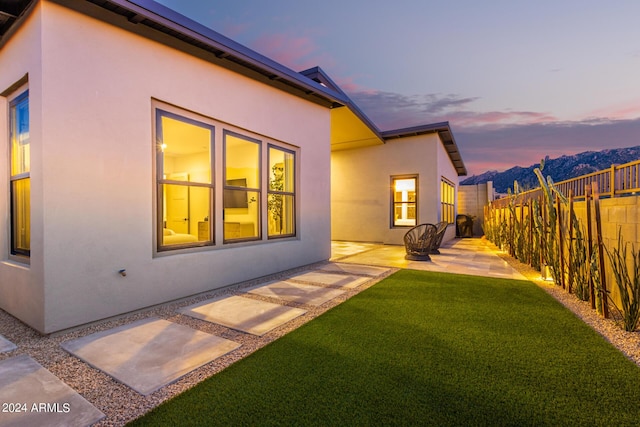 back house at dusk with a yard and a patio