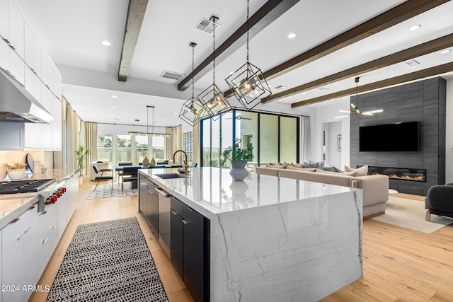 kitchen with hanging light fixtures, white cabinetry, a large island, and sink