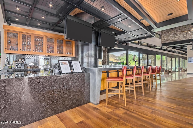 bar with beam ceiling and hardwood / wood-style floors