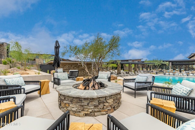 view of patio with a community pool and an outdoor living space with a fire pit