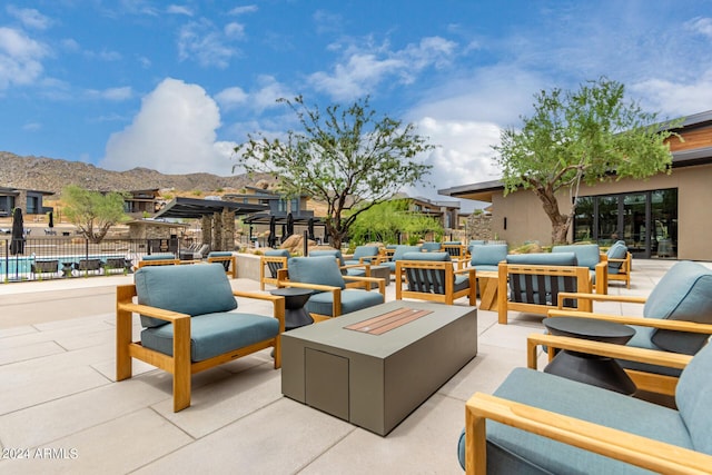 view of patio with a mountain view and an outdoor living space with a fire pit