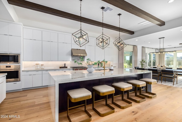 kitchen with built in microwave, hanging light fixtures, a large island, and stainless steel oven