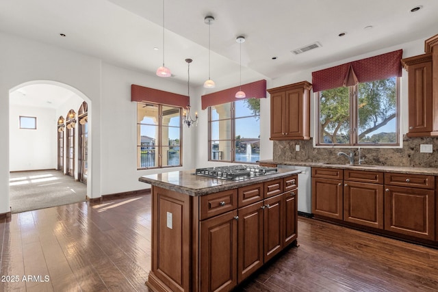 kitchen with sink, a center island, backsplash, a chandelier, and appliances with stainless steel finishes