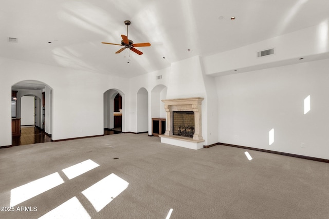 unfurnished living room featuring a large fireplace, ceiling fan, and carpet