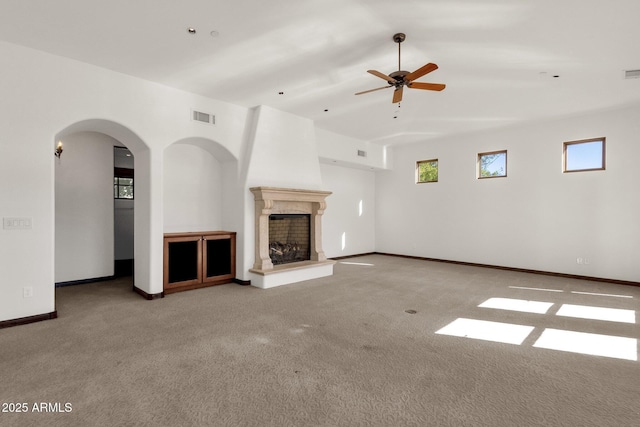 unfurnished living room with a large fireplace, ceiling fan, and carpet flooring