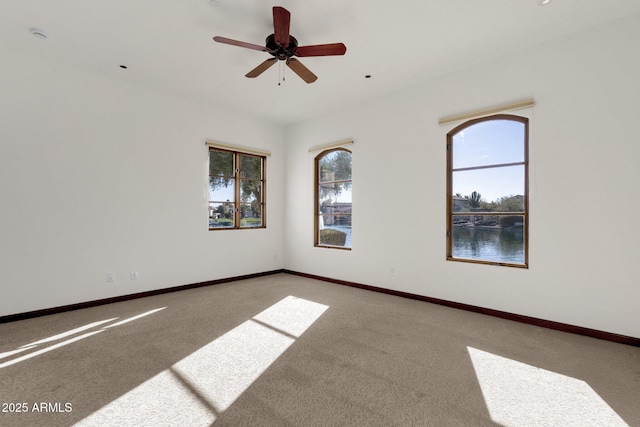 empty room featuring ceiling fan, carpet flooring, and a water view