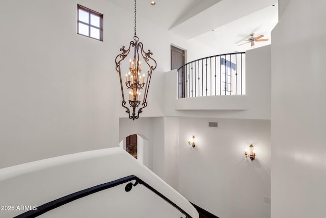 stairs with ceiling fan with notable chandelier and a healthy amount of sunlight