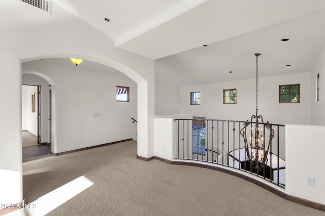 hallway featuring vaulted ceiling, a chandelier, and carpet