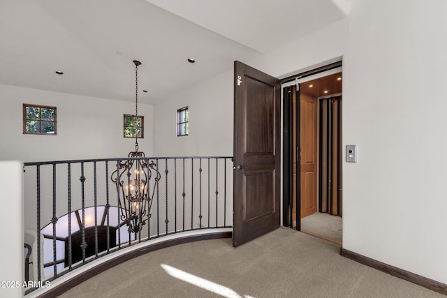 hall with carpet flooring and an inviting chandelier