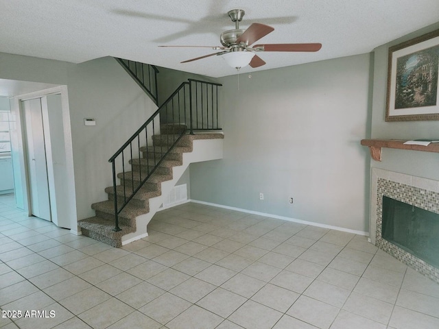 5704 E Aire Libre Ave Unit 1038, Scottsdale, AZ 85254 - staircase with ceiling fan, a fireplace, a textured ceiling, and tile patterned flooring