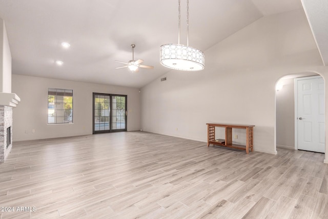 unfurnished living room featuring a fireplace, light wood-type flooring, high vaulted ceiling, and ceiling fan