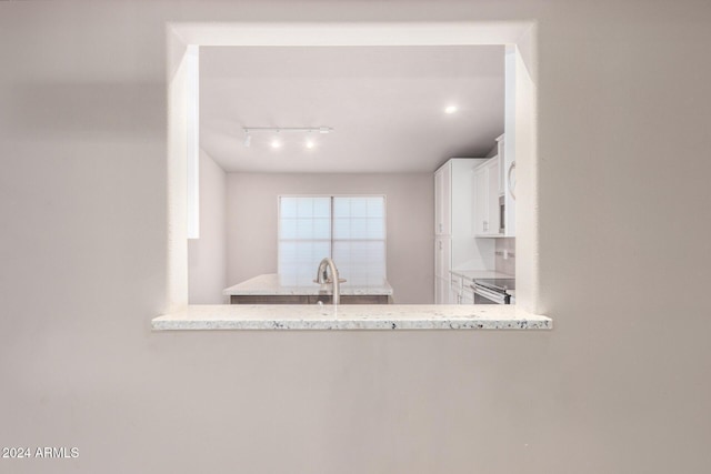 kitchen with white cabinetry, light stone counters, sink, and stainless steel electric range oven