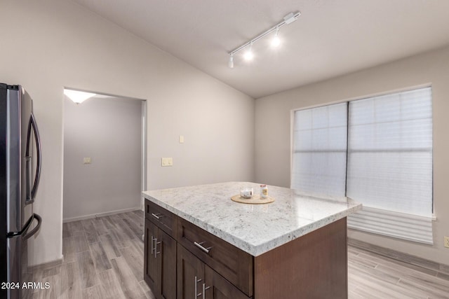 kitchen featuring stainless steel refrigerator, dark brown cabinetry, rail lighting, a kitchen island, and light wood-type flooring