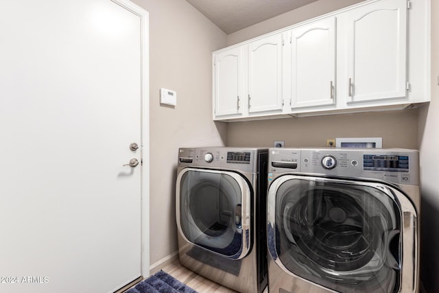 laundry area with washing machine and dryer, cabinets, a textured ceiling, and hardwood / wood-style flooring