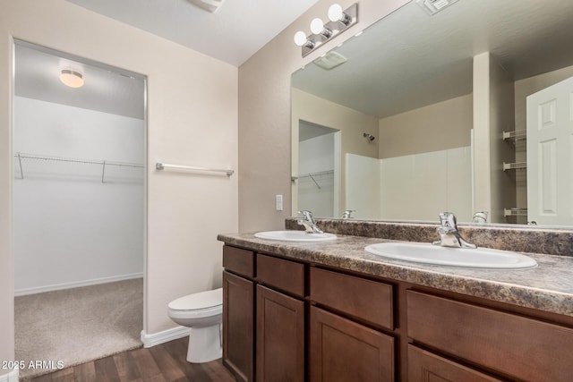 full bathroom featuring a spacious closet, toilet, wood finished floors, and a sink