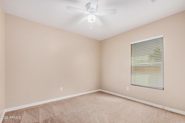 carpeted spare room with a ceiling fan and baseboards