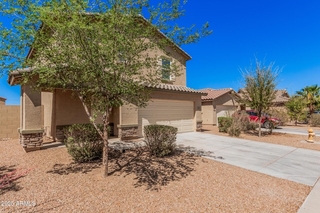 view of front of house featuring concrete driveway, an attached garage, a tiled roof, and stucco siding