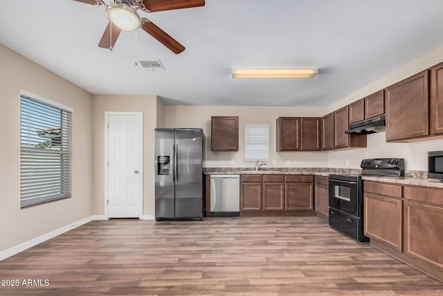 kitchen featuring under cabinet range hood, visible vents, a sink, light wood-style floors, and appliances with stainless steel finishes
