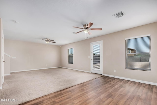 spare room with baseboards, a ceiling fan, wood finished floors, and visible vents