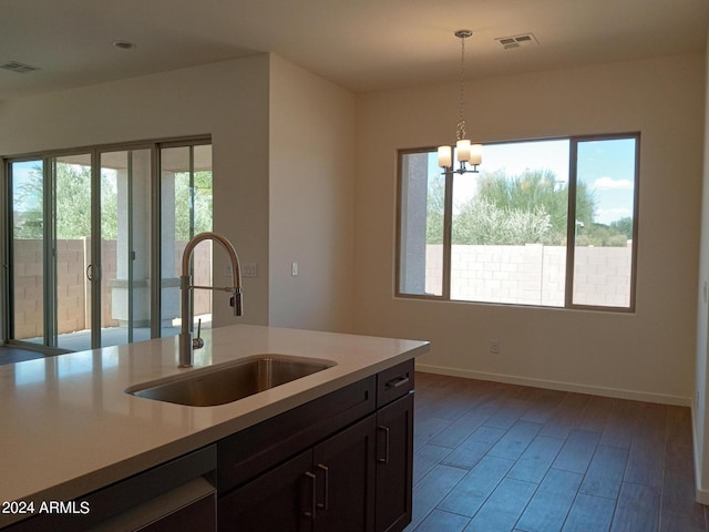 kitchen featuring pendant lighting, sink, wood-type flooring, dark brown cabinets, and a notable chandelier