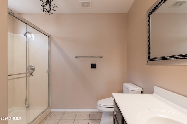 bathroom with a shower with door, vanity, toilet, and tile patterned floors