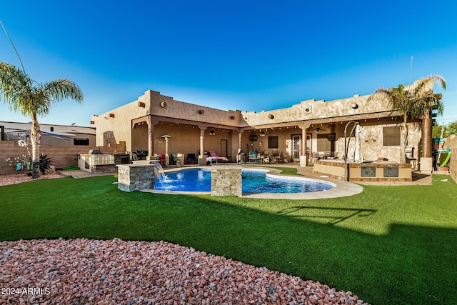 view of pool featuring a yard, a patio, ceiling fan, and an outdoor kitchen