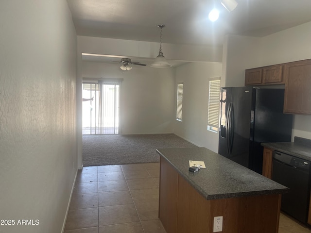 kitchen featuring decorative light fixtures, a center island, ceiling fan, black appliances, and light colored carpet