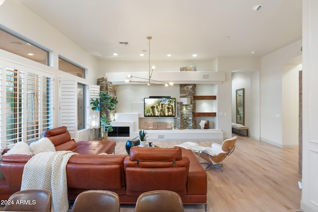 living room with a notable chandelier, a fireplace, and light hardwood / wood-style flooring