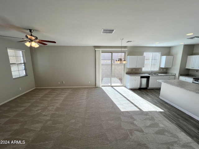 unfurnished living room featuring sink, carpet floors, and ceiling fan with notable chandelier