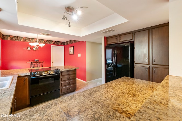 kitchen featuring hanging light fixtures, black appliances, dark brown cabinets, kitchen peninsula, and a raised ceiling