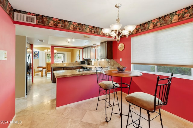 kitchen featuring stainless steel appliances, kitchen peninsula, a chandelier, and a healthy amount of sunlight