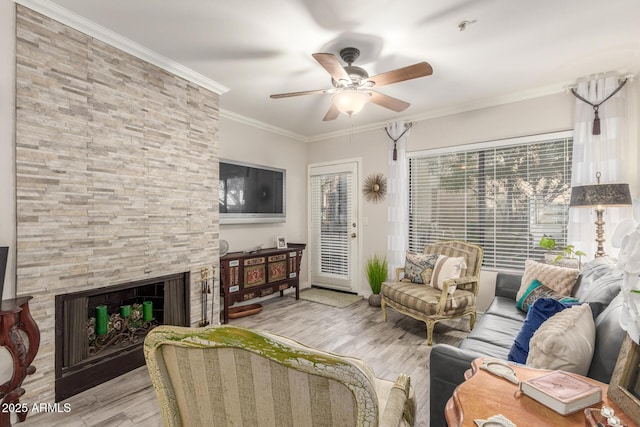 living room with crown molding, ceiling fan, a fireplace, and light hardwood / wood-style flooring