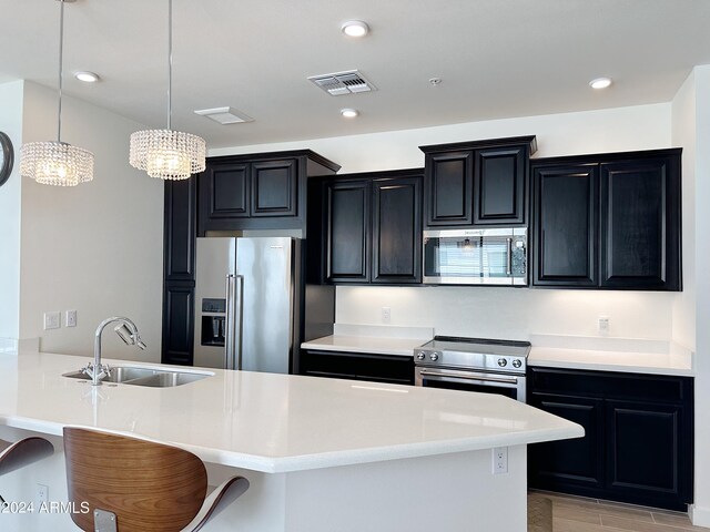 kitchen with a breakfast bar area, a notable chandelier, hanging light fixtures, high end appliances, and sink