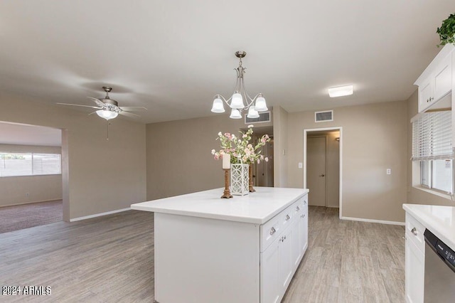 kitchen with white cabinets, hanging light fixtures, stainless steel dishwasher, light hardwood / wood-style floors, and a kitchen island