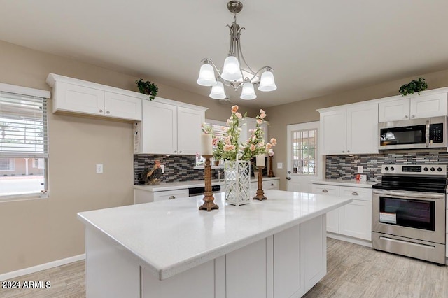 kitchen featuring appliances with stainless steel finishes, decorative light fixtures, white cabinets, and a center island