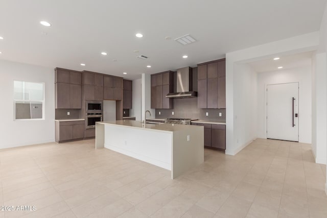 kitchen with stainless steel appliances, a sink, wall chimney exhaust hood, and modern cabinets