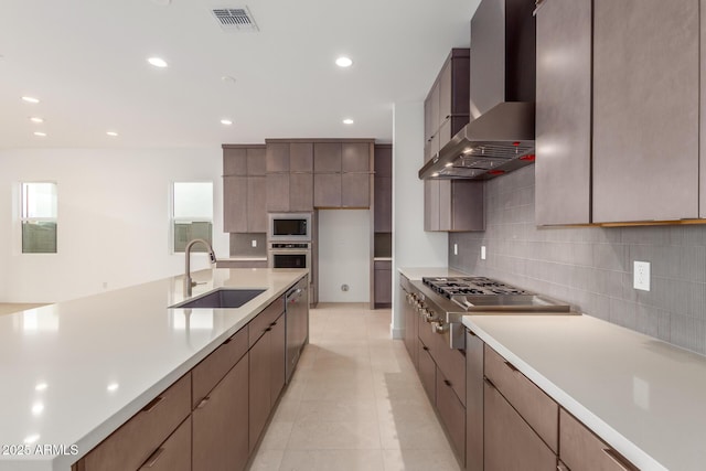 kitchen featuring stainless steel appliances, visible vents, a sink, modern cabinets, and wall chimney exhaust hood