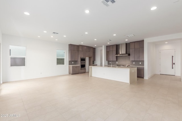 kitchen with light countertops, visible vents, appliances with stainless steel finishes, modern cabinets, and wall chimney exhaust hood