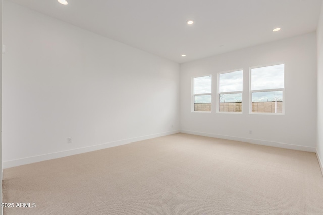 empty room featuring light carpet, baseboards, and recessed lighting