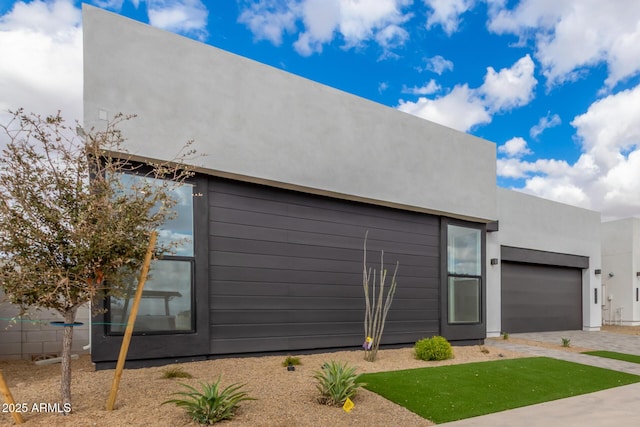 view of side of property with driveway, a garage, and stucco siding