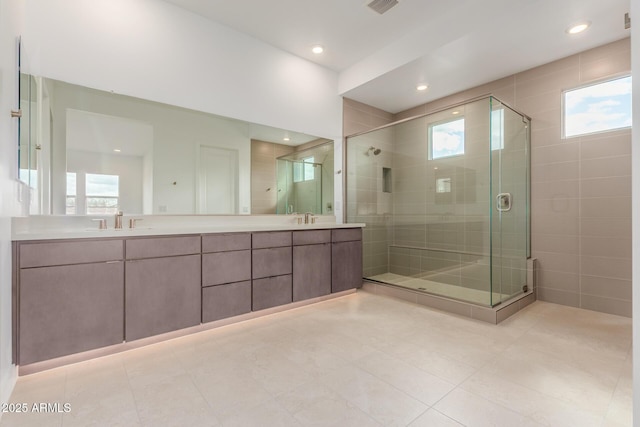 full bathroom with double vanity, a shower stall, visible vents, and a sink