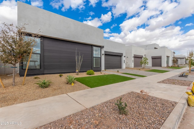 pueblo revival-style home featuring a garage, driveway, and stucco siding